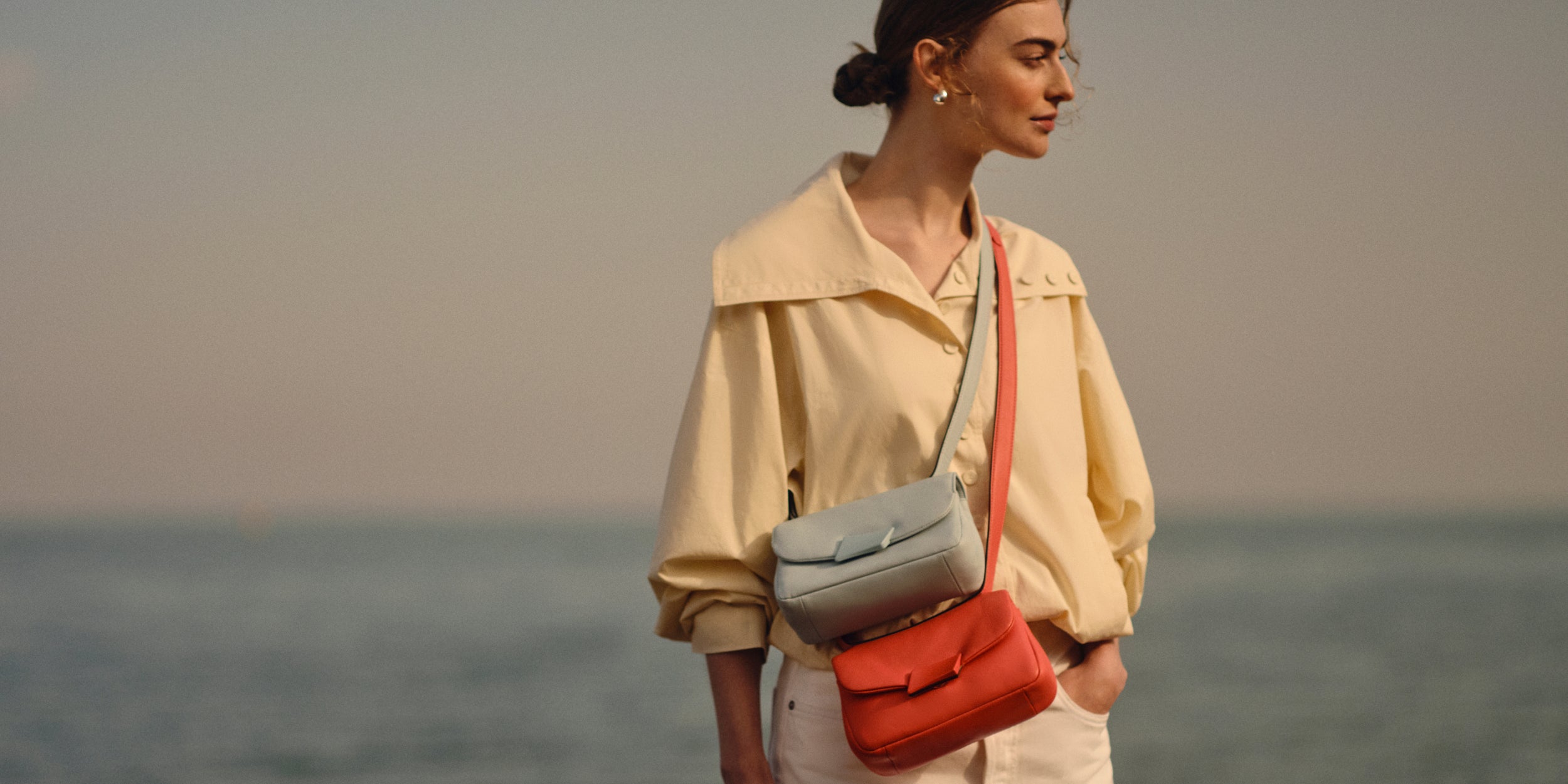 Woman holding two handbags against a blurred natural background