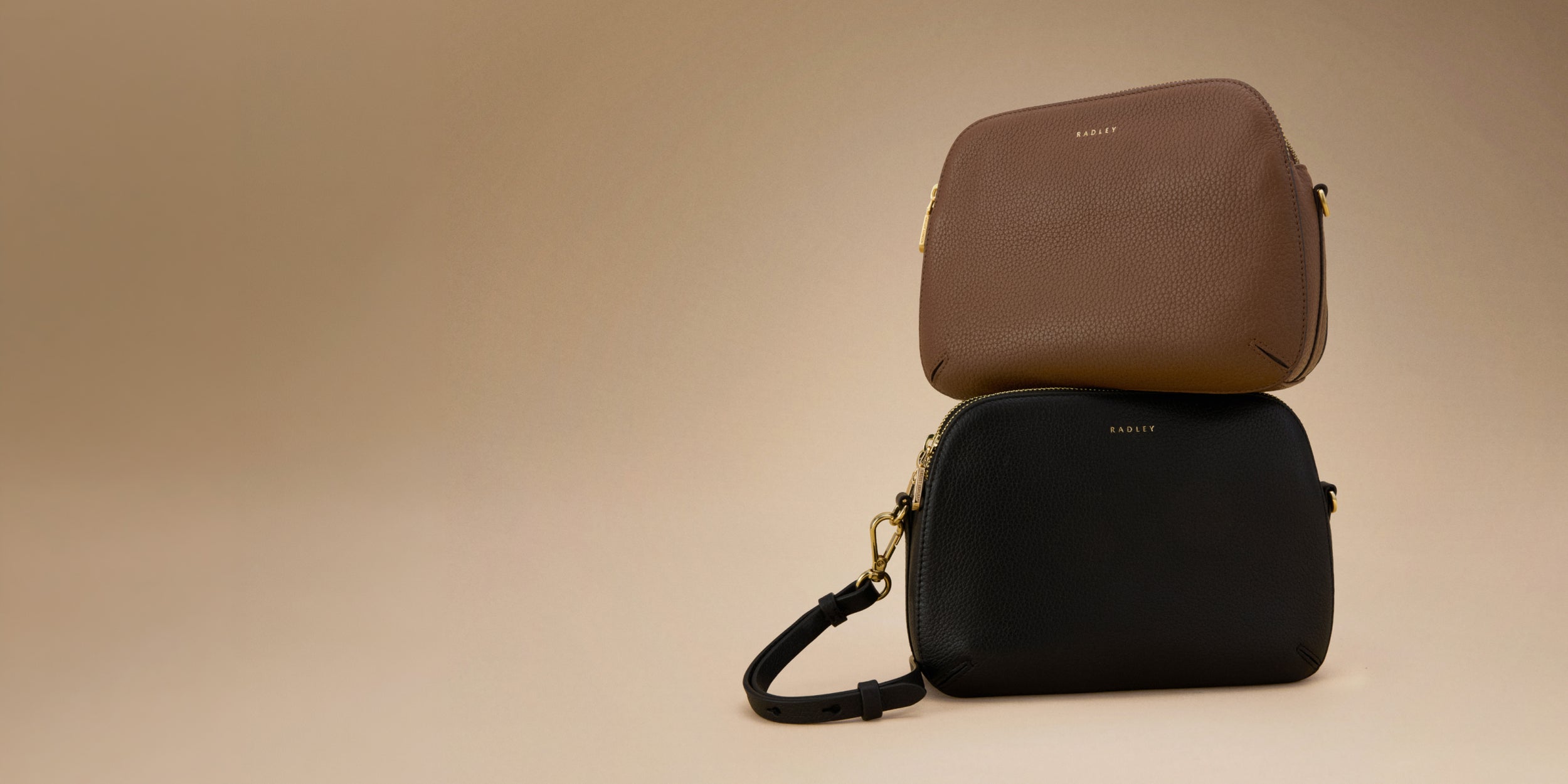 Two bags, one brown and one black, stacked on a beige background