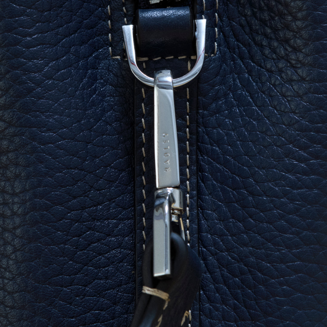 Close-up of a silver zipper on a dark blue leather bag
