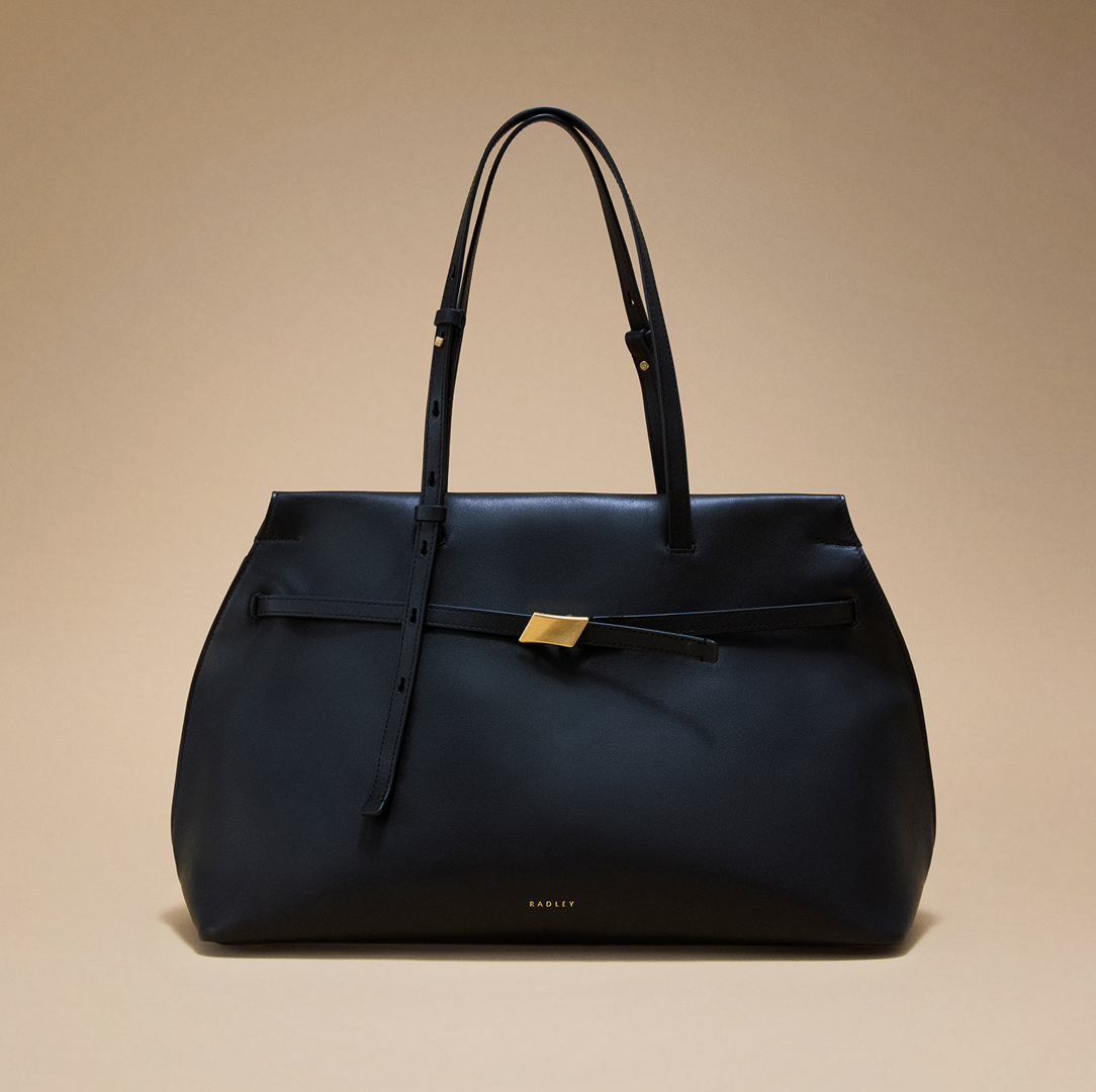 Black handbag with a gold clasp on a beige background