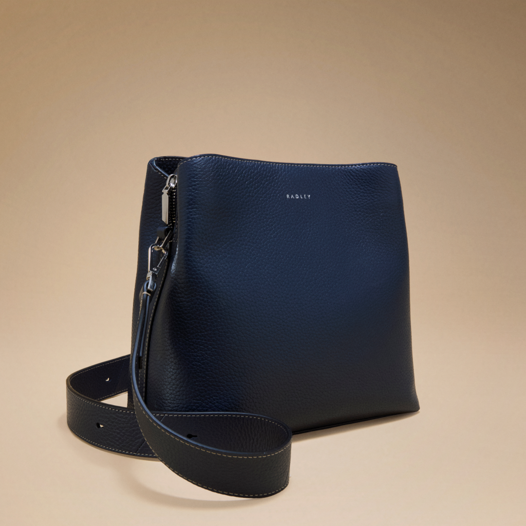 Navy blue handbag with a strap on a beige background