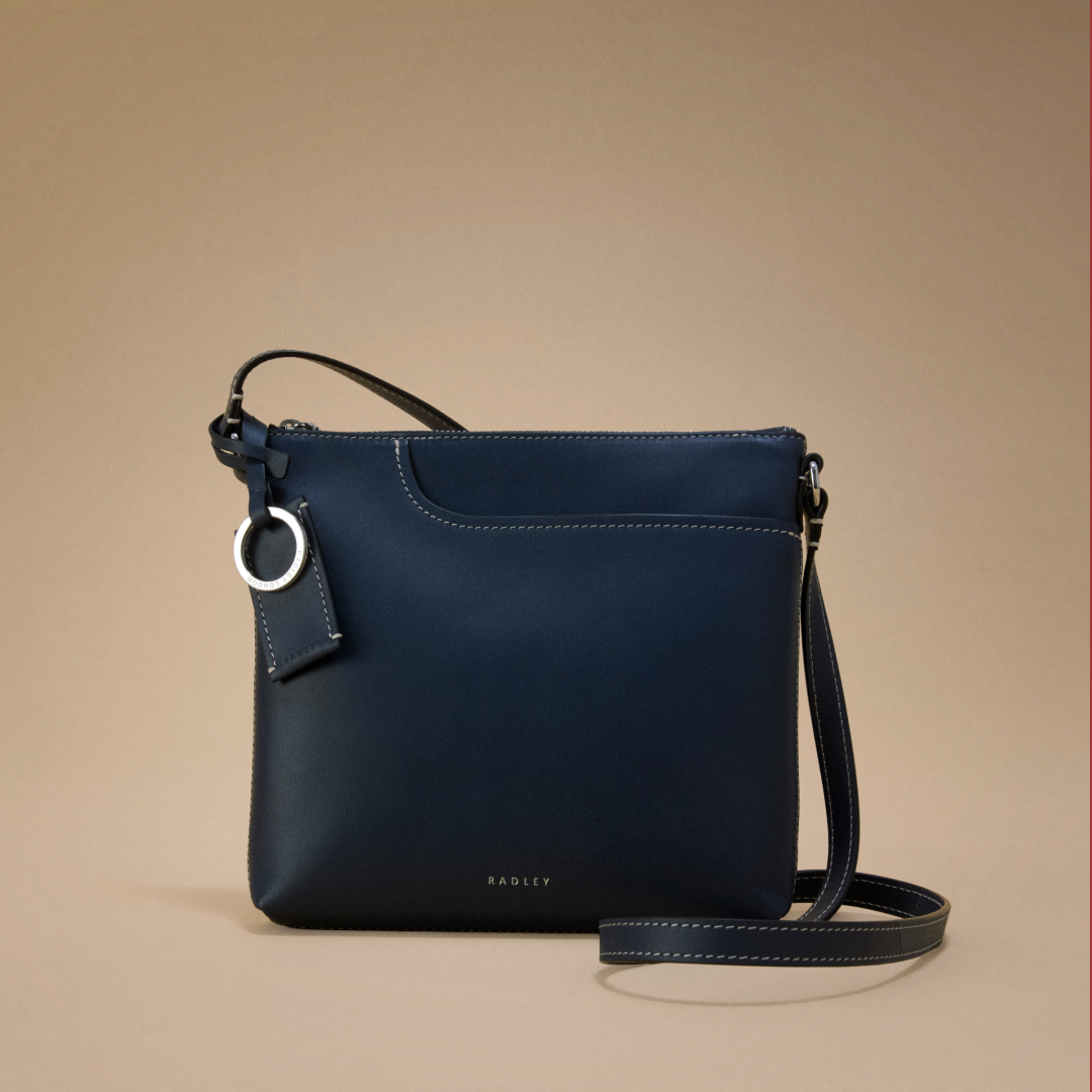 Navy blue handbag with a strap on a beige background