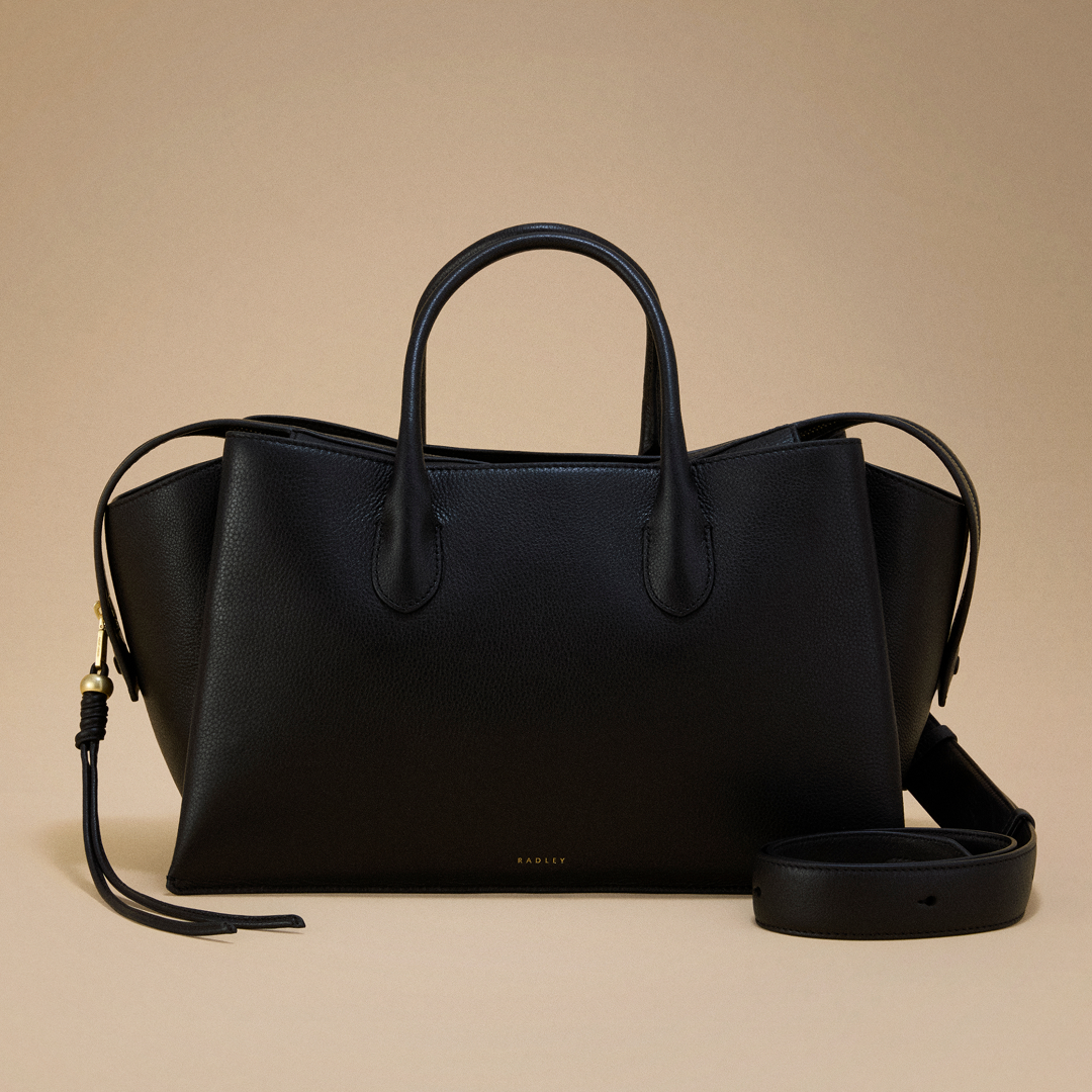 Black leather handbag with a strap on a beige background