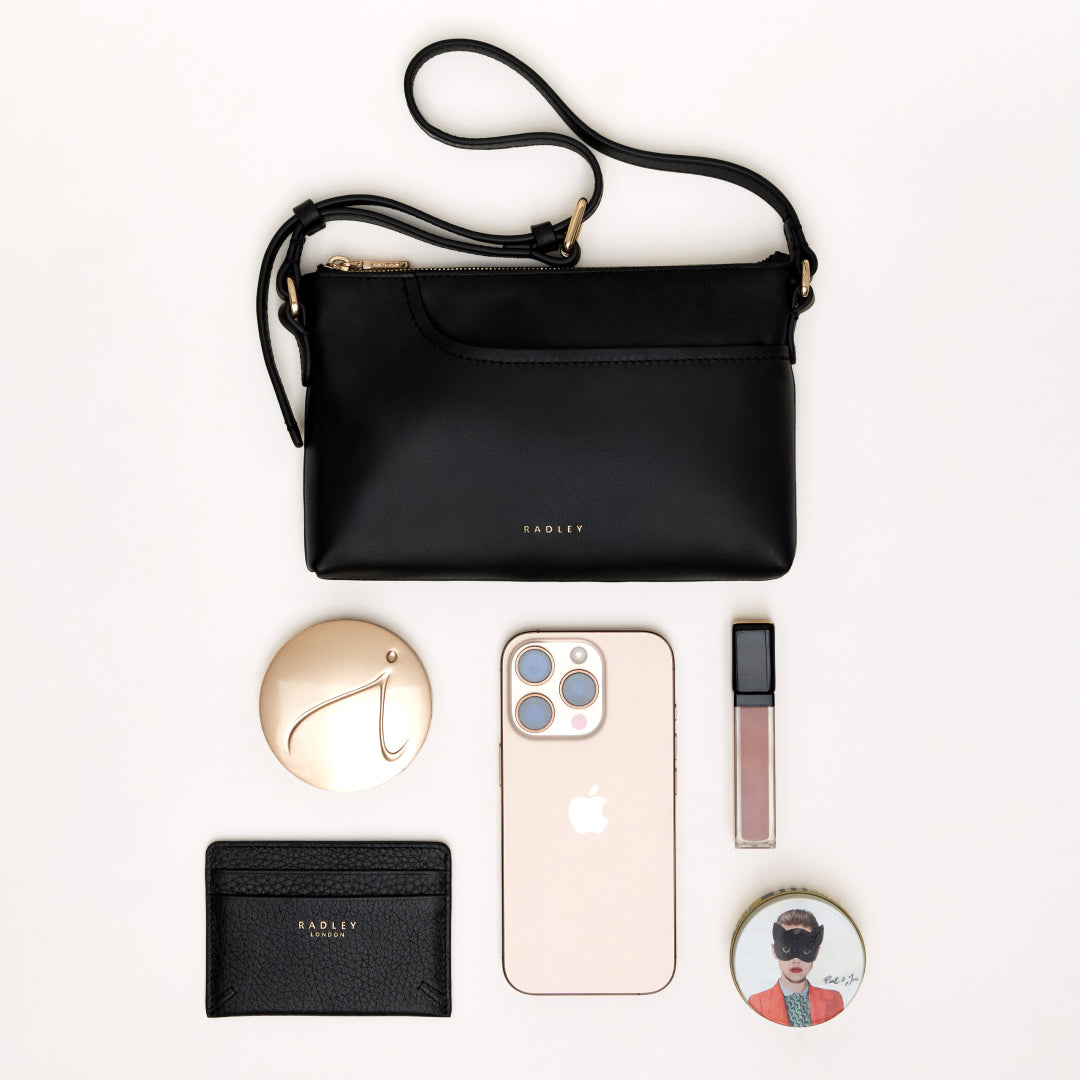 Black handbag with Radley branding, phone, wallet, and other accessories on a white background