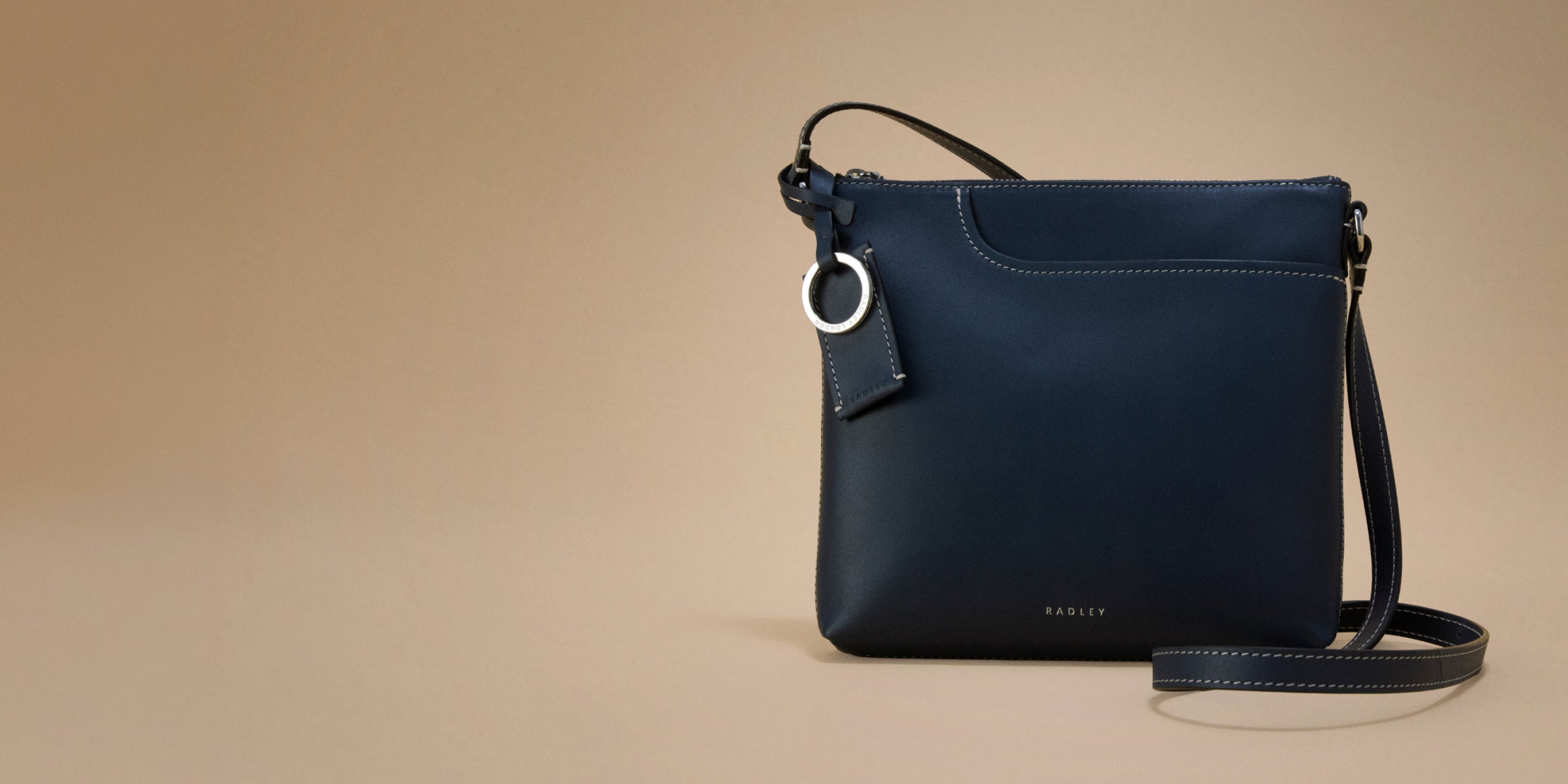 Navy blue handbag with a strap on a beige background