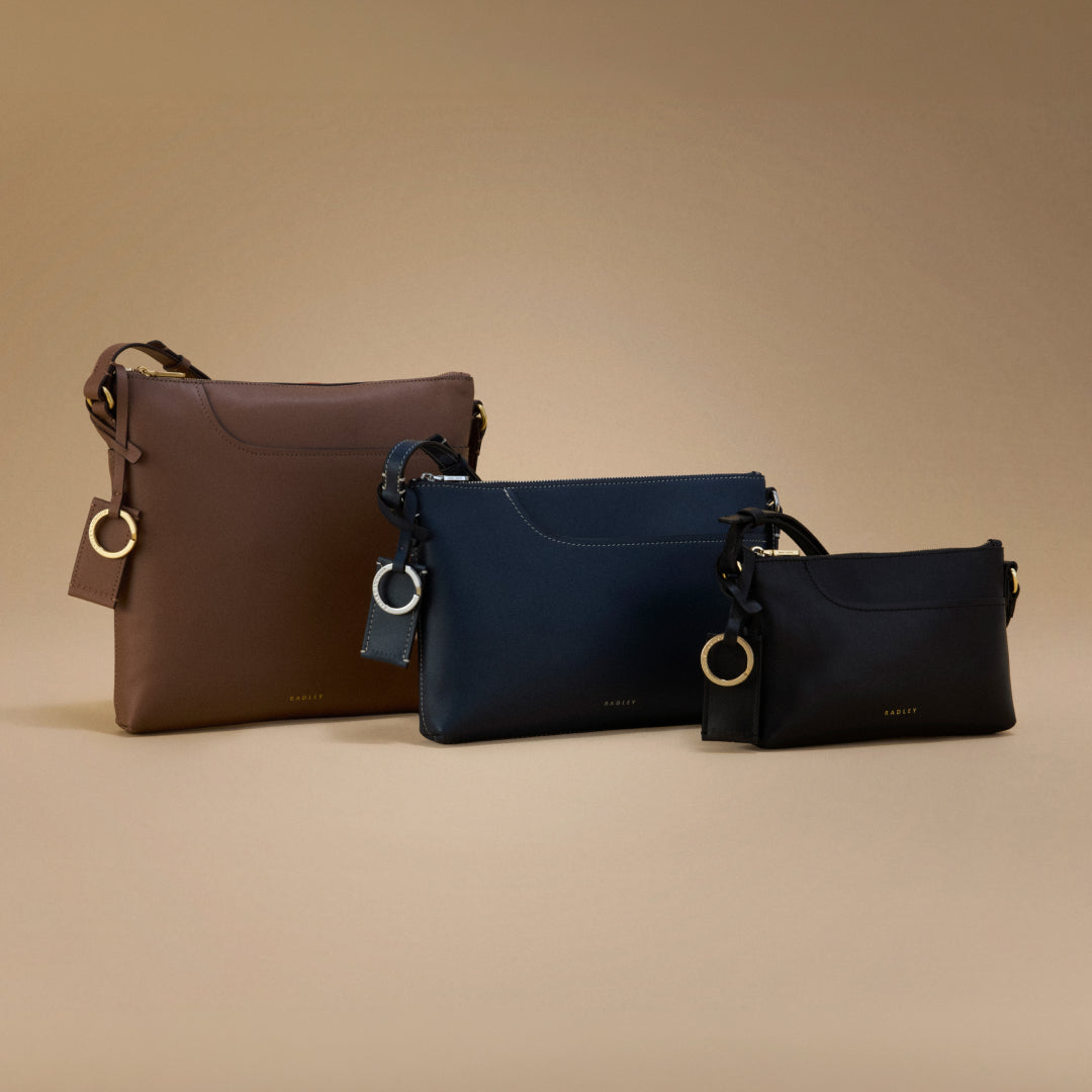 Three handbags in brown, blue, and black on a beige background