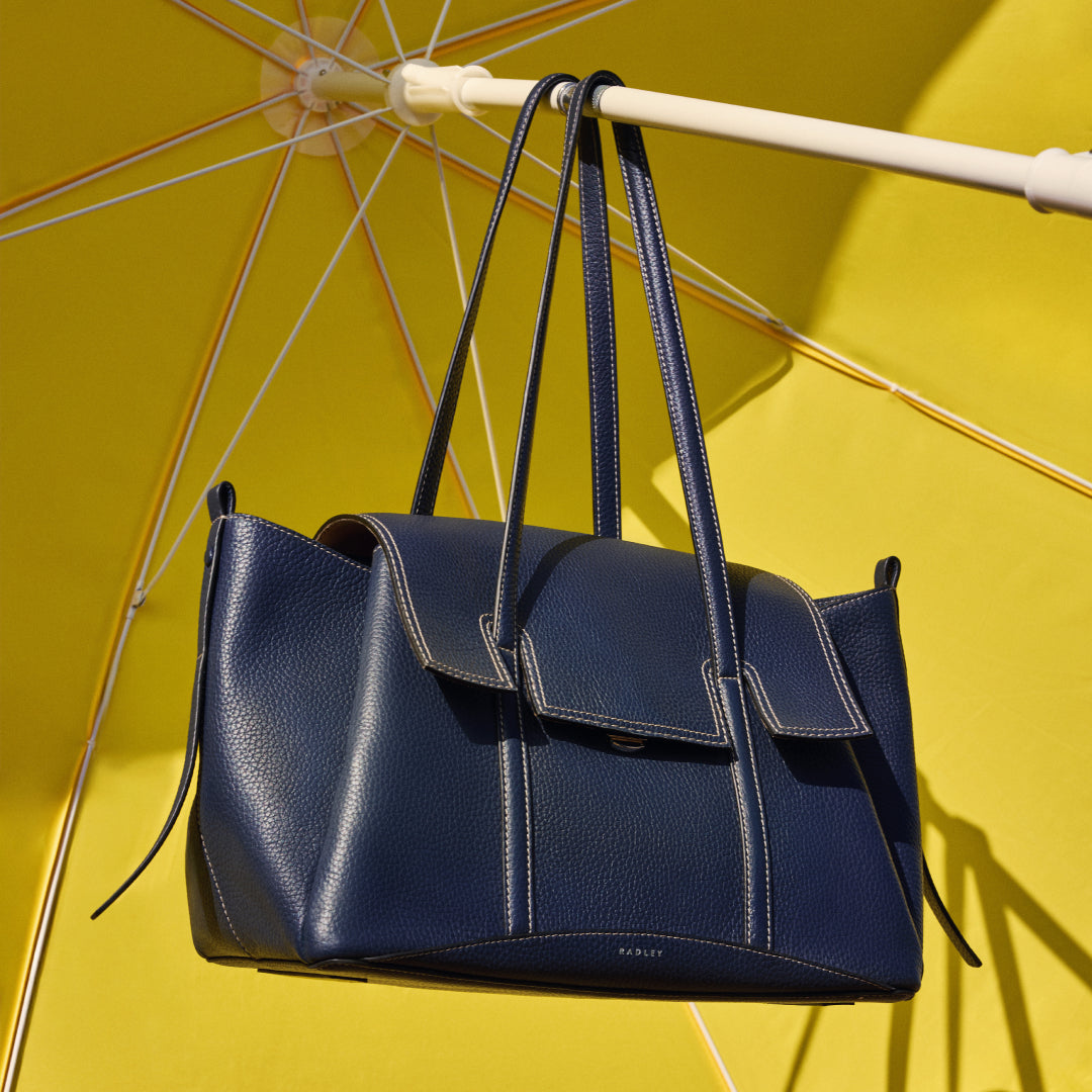 Blue handbag hanging from a yellow umbrella