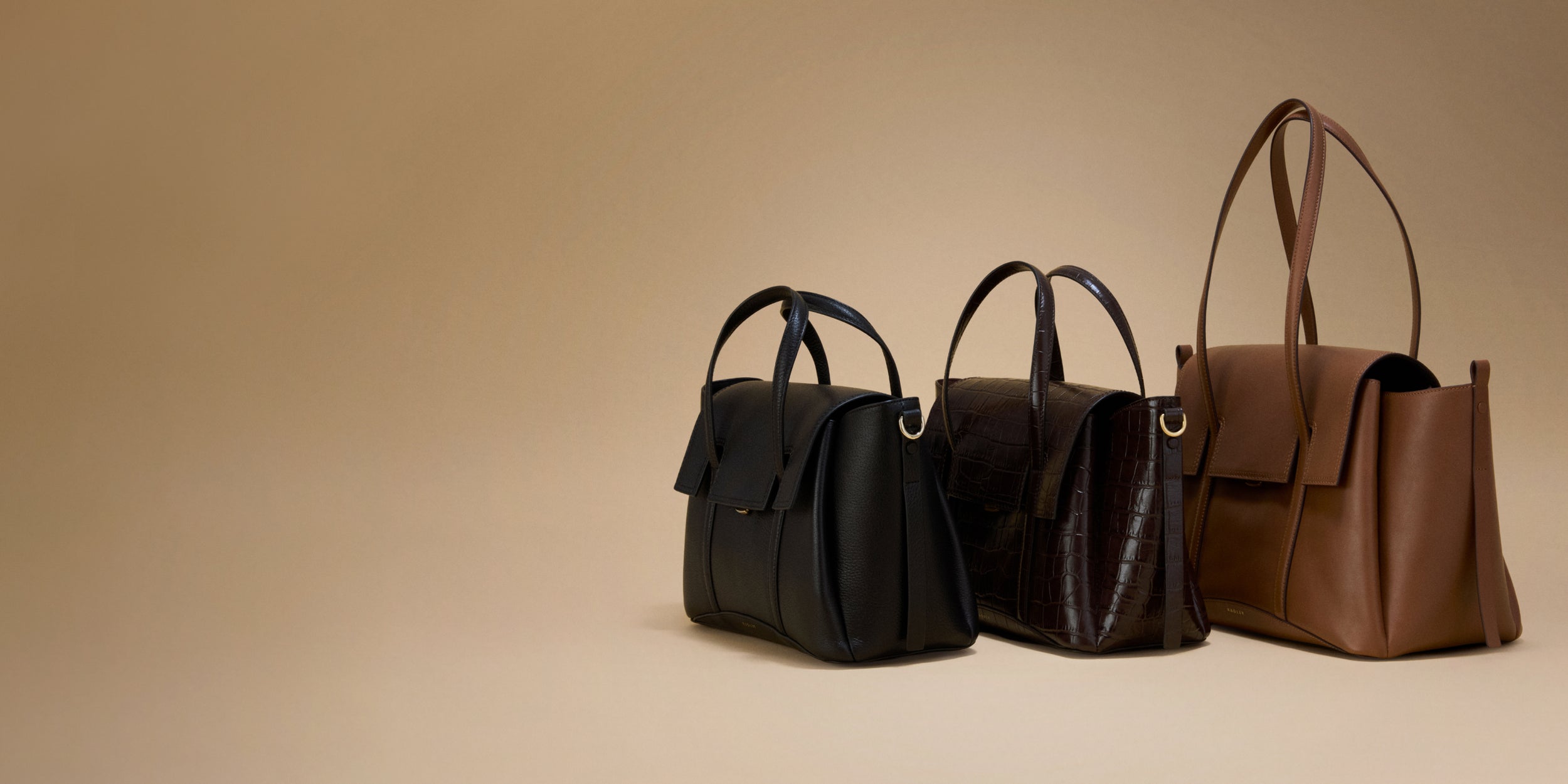 Three handbags in black, brown, and dark brown on a beige background