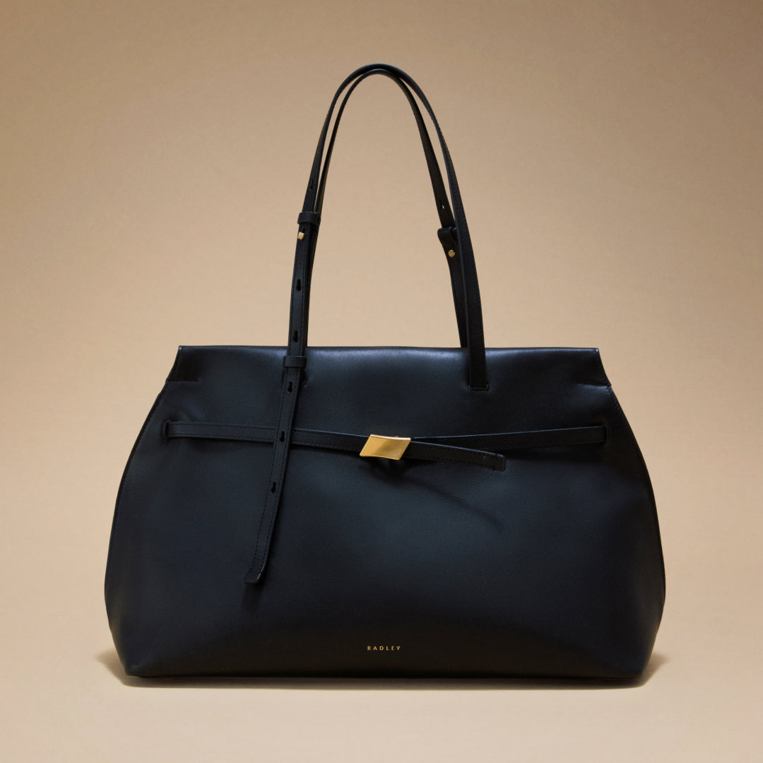 Black handbag with a gold clasp on a beige background