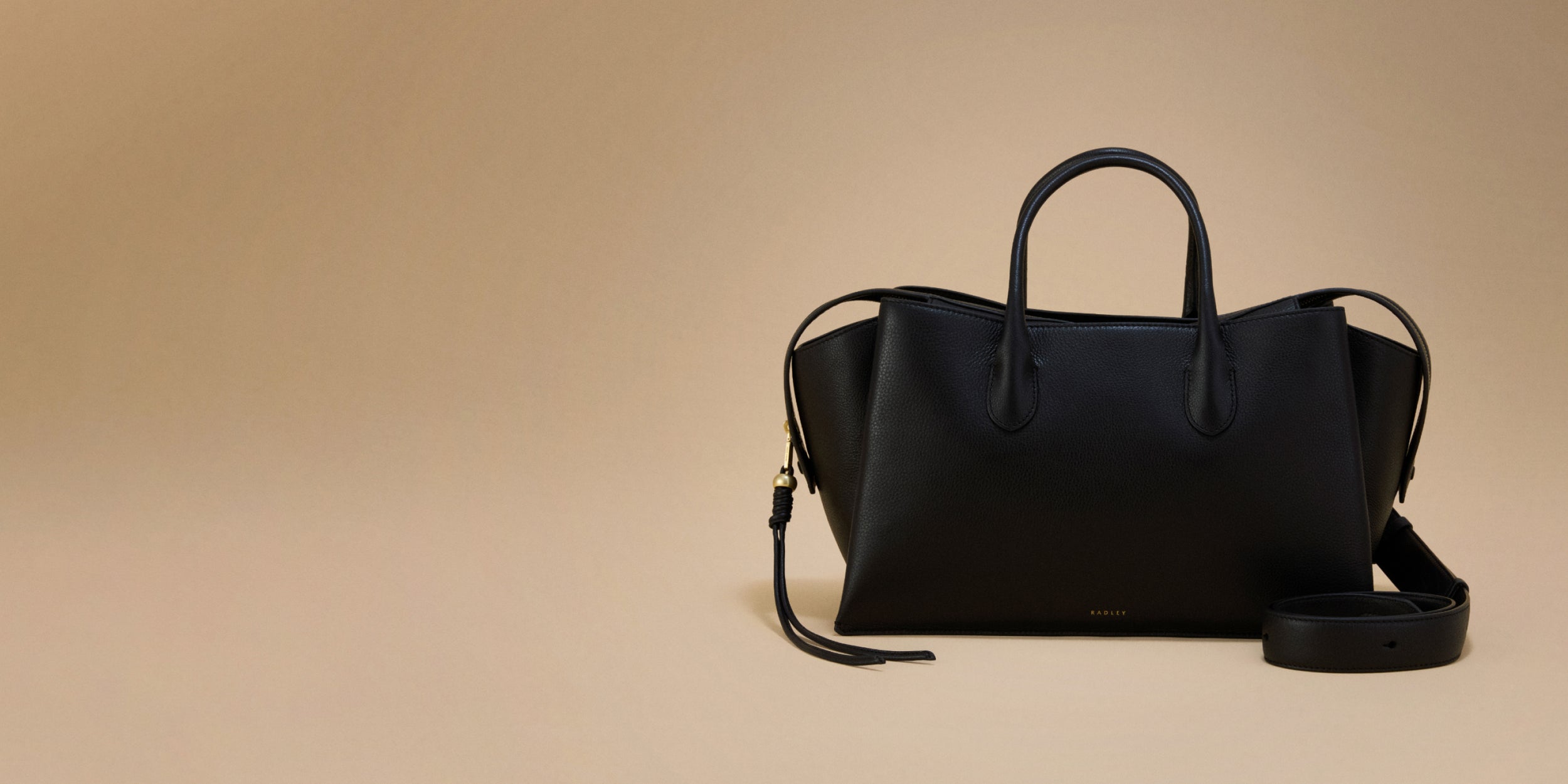 Black handbag with a strap on a beige background