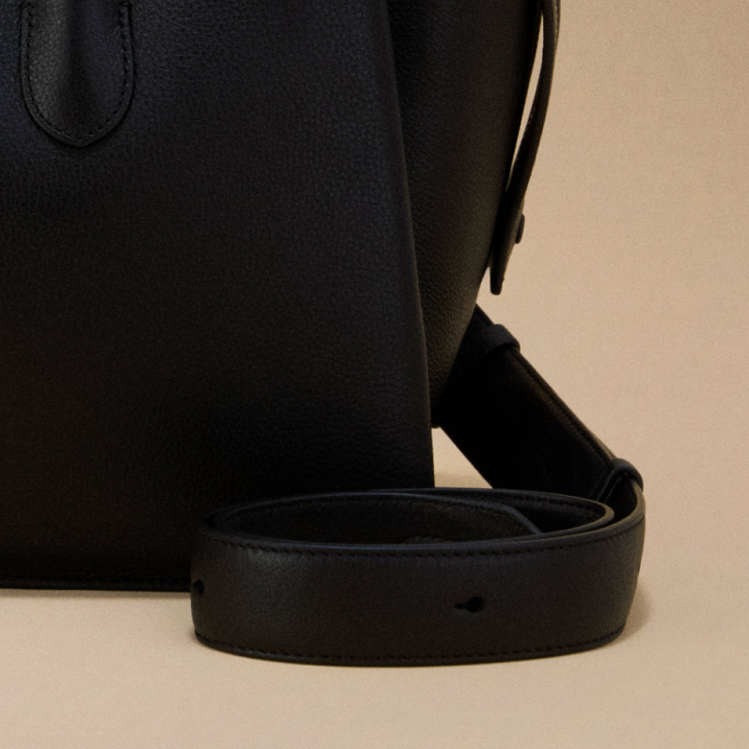 Close-up of a black leather strap on a beige background