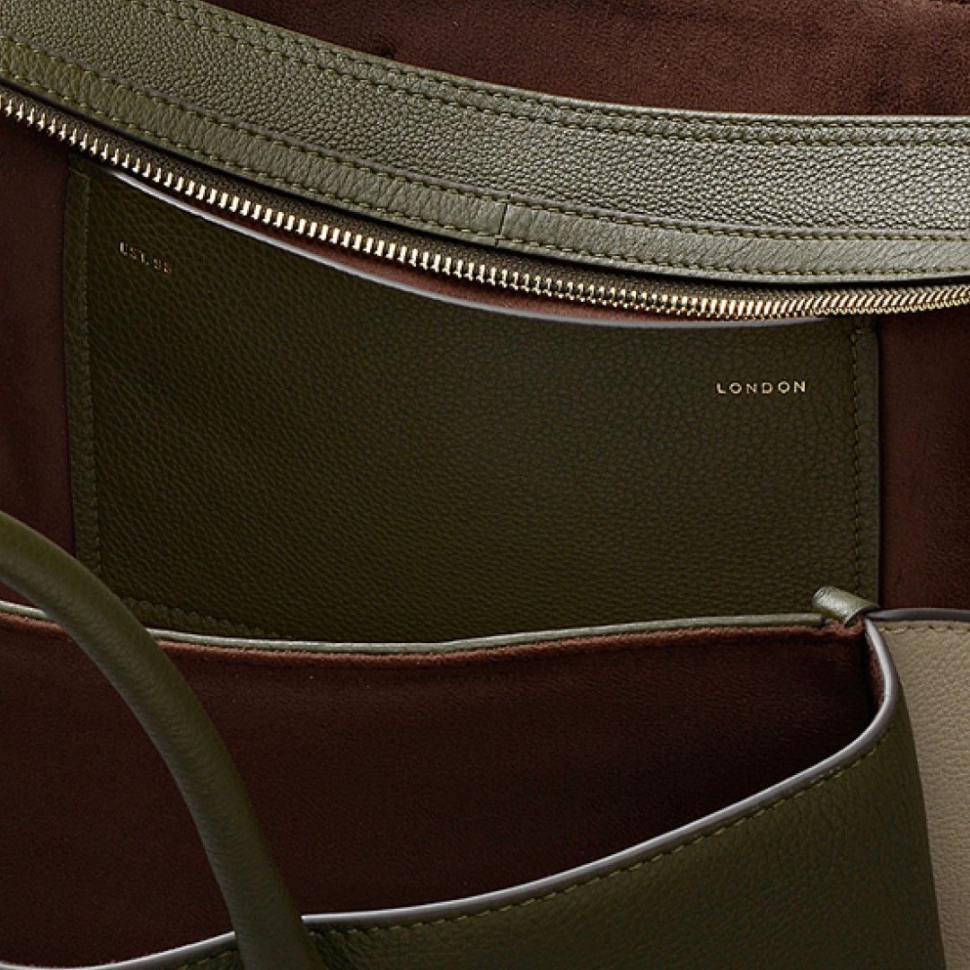 Close-up of a brown and green leather bag with 'London' branding.