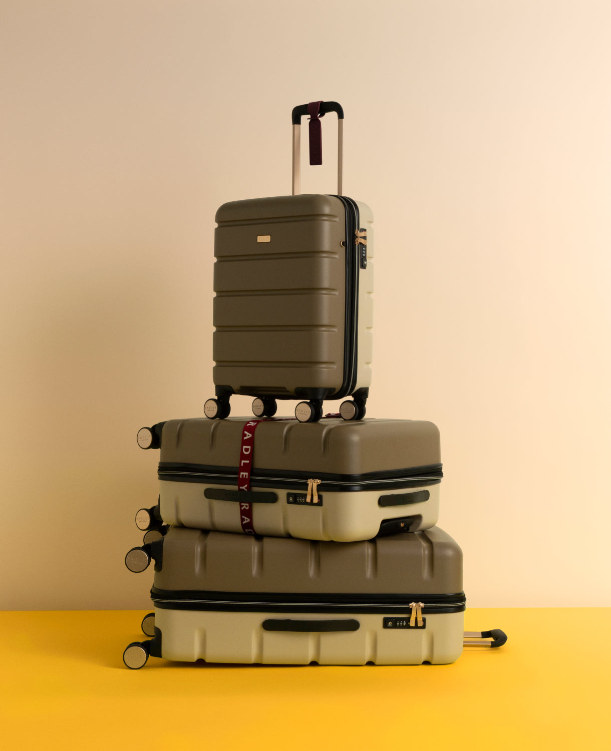 Stack of suitcases on a yellow surface with a beige background