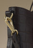 Close-up of a black croc-effect leather bag with gold-tone clip hardware and a detachable strap.