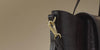 Close-up of a black croc-effect leather bag with gold-tone clip hardware and a detachable strap.